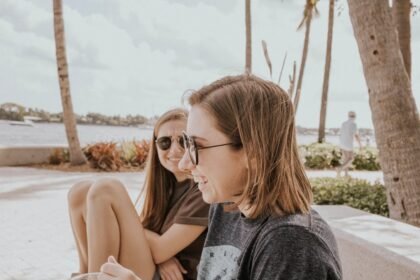 two women sitting beside each other by the beach